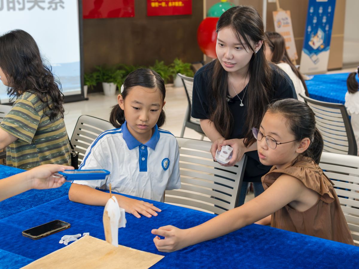A teacher kneeling beside pupils to help them build a balanced meal with the cards